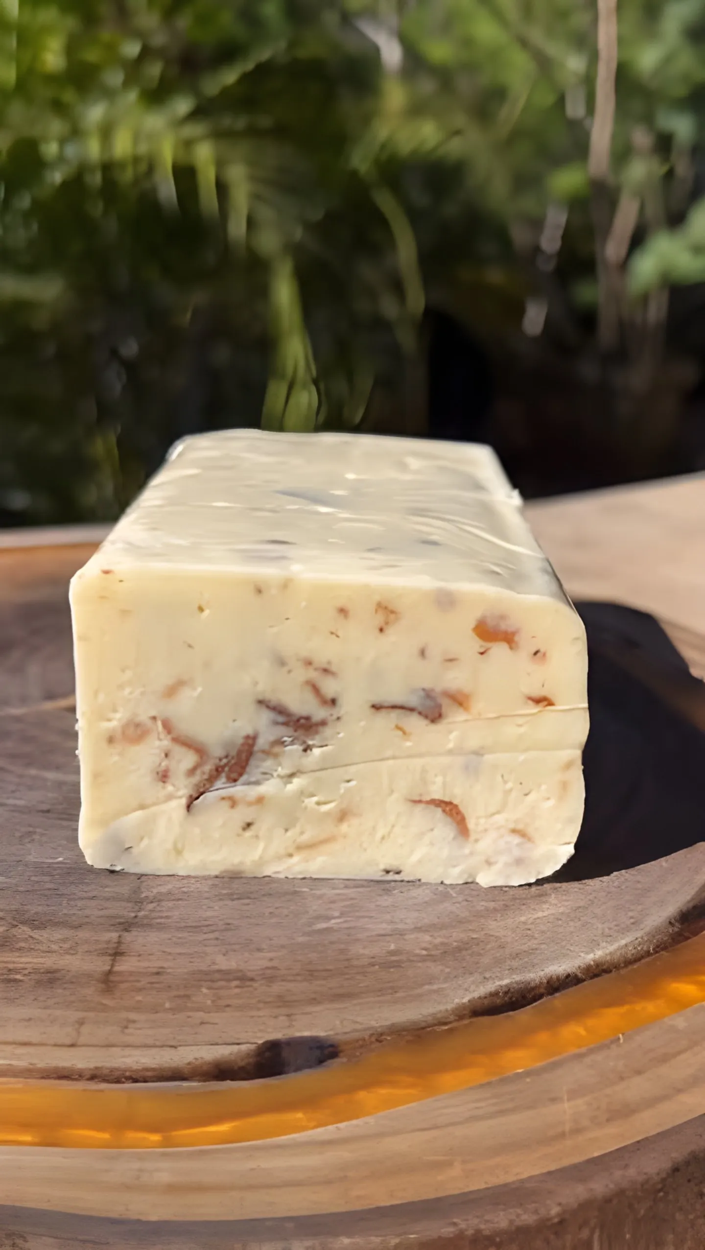 Barra de queijo cortada sobre tábua de madeira